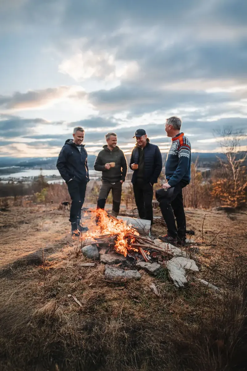 Fire kollegaer rundt et bål med utsikt